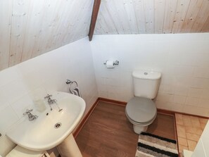 Ein kleines Badezimmer mit Waschbecken, Toilette und Holzboden.
