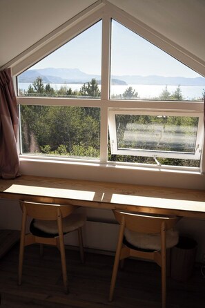 A room with a desk and two chairs, a large window with a view of a lake and mountains, and a curtain on the left. - A Historic Icelandic Lakeside Home, where nature and people reconnect (Selfoss)