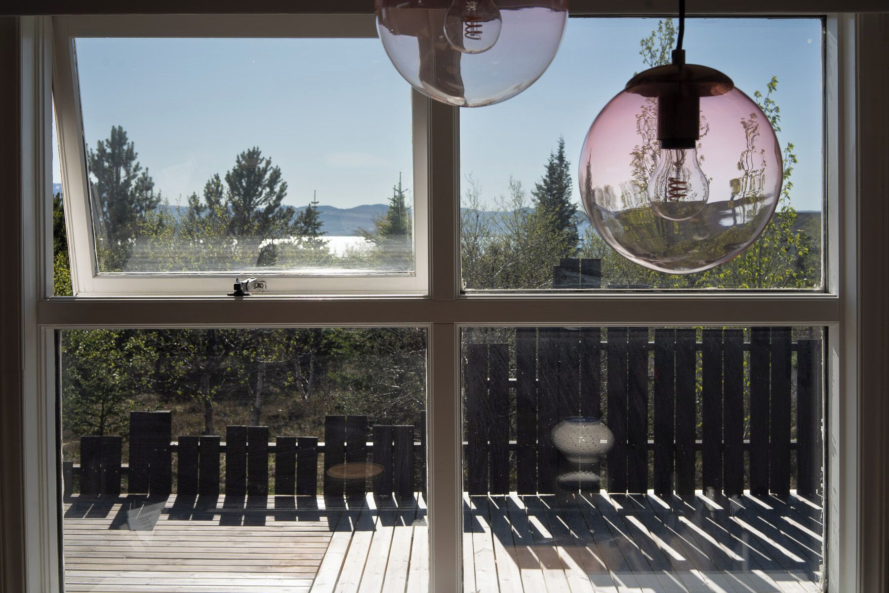 Et værelse med tre vinduer, en træterrasse og en hængende lampe.