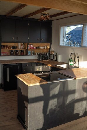 A kitchen with dark cabinets, a wooden countertop, a built-in stove, and a window with a view. - A Historic Icelandic Lakeside Home, where nature and people reconnect (Selfoss)