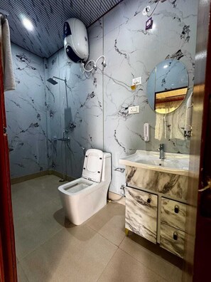 A bathroom with a toilet, a sink, a mirror, and a shower.
