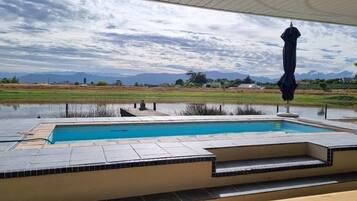 A swimming pool with a view of mountains and a cloudy sky.