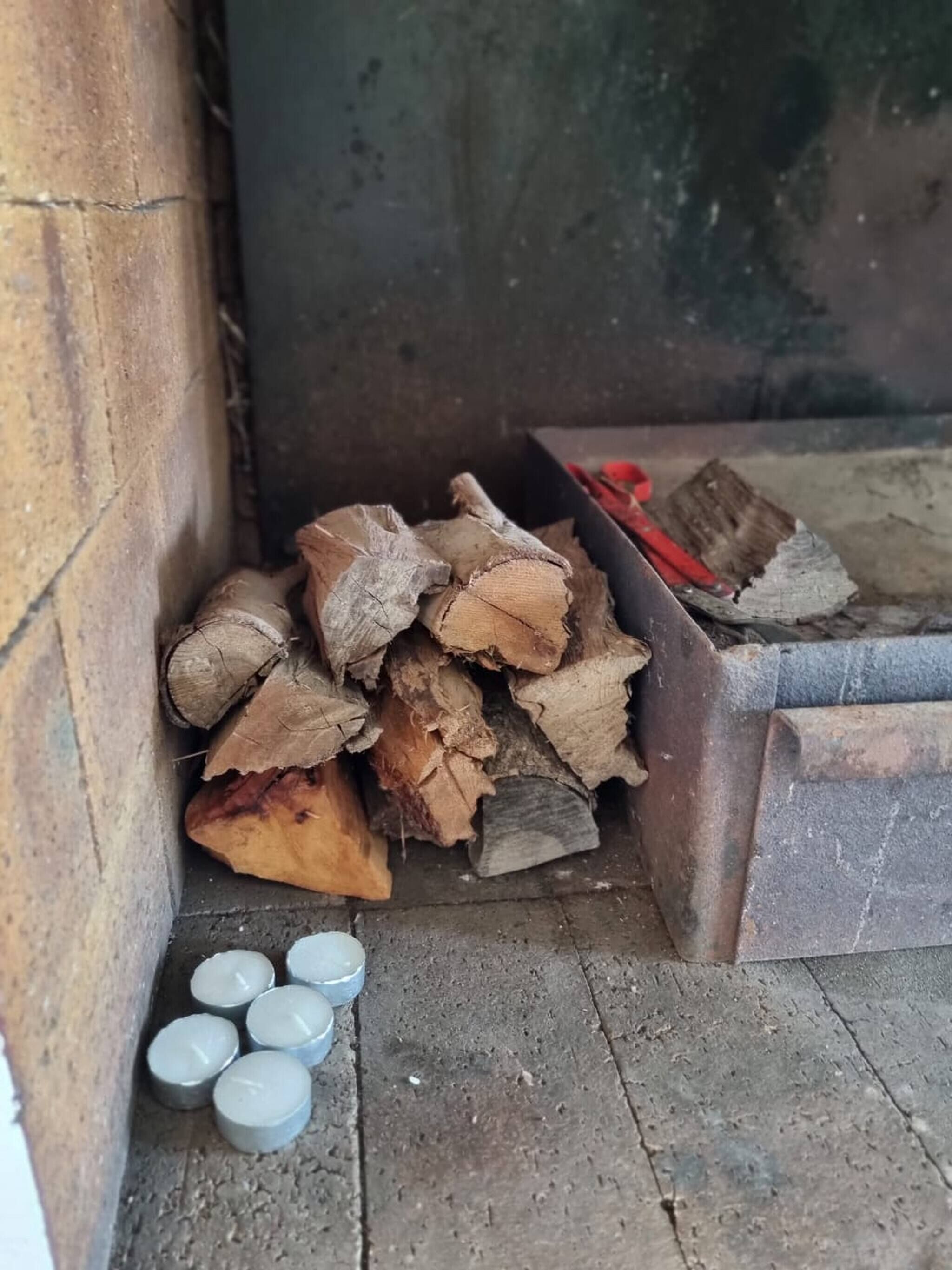 A stack of firewood and metal containers on a concrete floor.