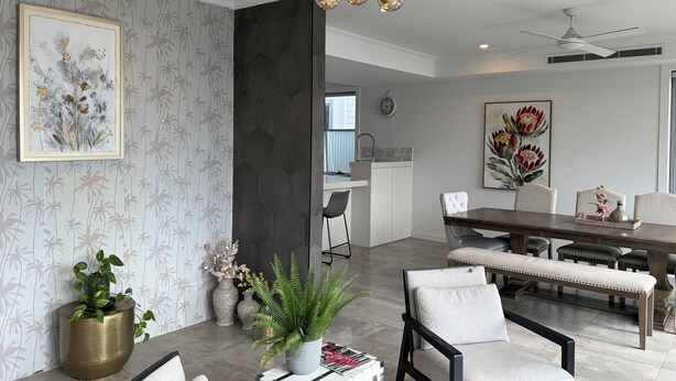 Ein modernes Wohnzimmer mit Essbereich, ausgestattet mit einer Kronleuchter, Kunstwerken und einem Blumentopf.