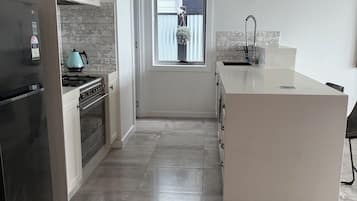 A modern kitchen with a stainless steel refrigerator, a gas stove, and a white island.