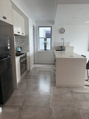 A modern kitchen with a stainless steel refrigerator, a gas stove, and a white island.