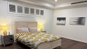 Ein Schlafzimmer mit einem Bett, zwei Nachttischen, einem Wandlüfter und zwei Wandbildern.