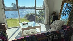 Ein Wohnzimmer mit einer Couch, einem Glastisch und Blick auf einen See.
