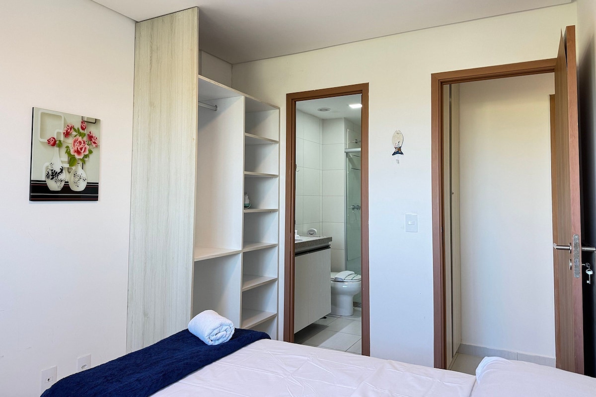 Ein Hotelzimmer mit Bett, einem Badezimmer mit Dusche und einem Kleiderschrank mit Regalen.