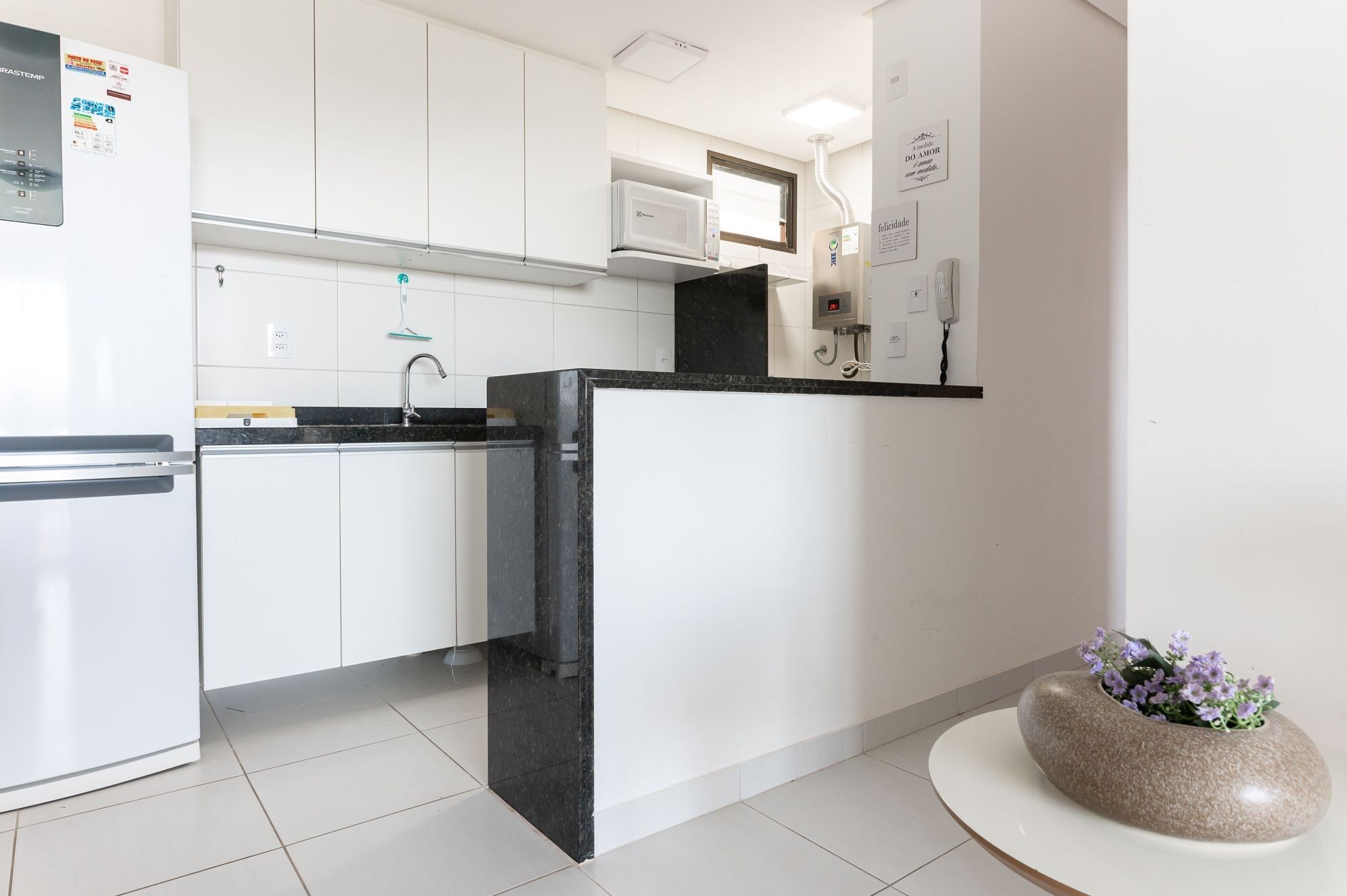 Una cocina moderna con armarios blancos, encimera negra y microondas integrado.