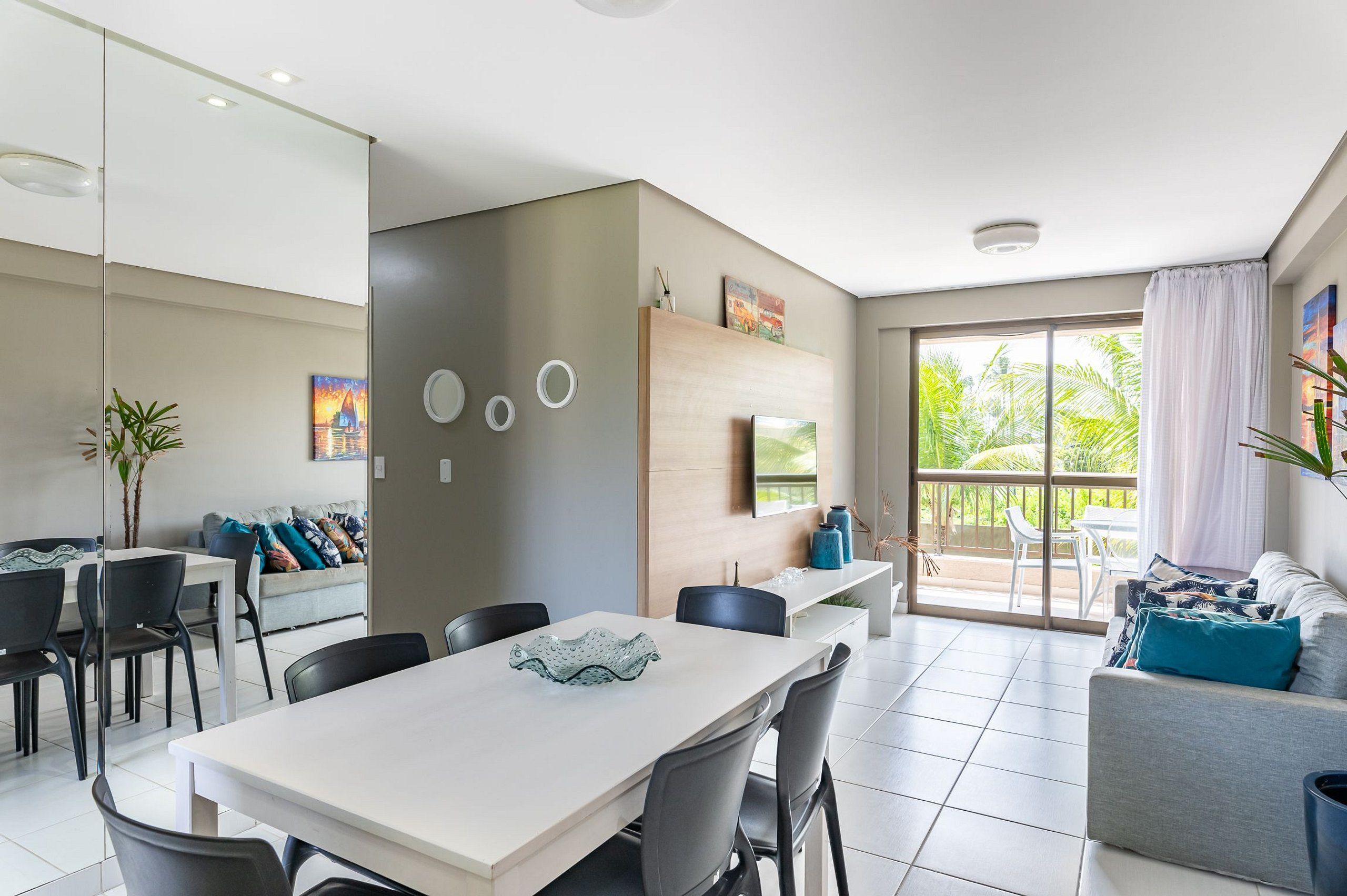 Un espacio de estar moderno con comedor, sofá y balcón con vistas a zonas verdes.