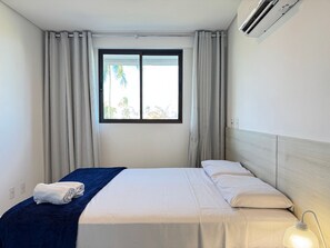 A hotel room with a bed, curtains, a window, and an air conditioning unit. - BeachClass EcoLife Porto de Galinhas (Ipojuca)