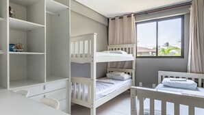 Ein Schlafsaal mit Etagenbetten, einem Schreibtisch und einem Fenster mit Vorhängen.