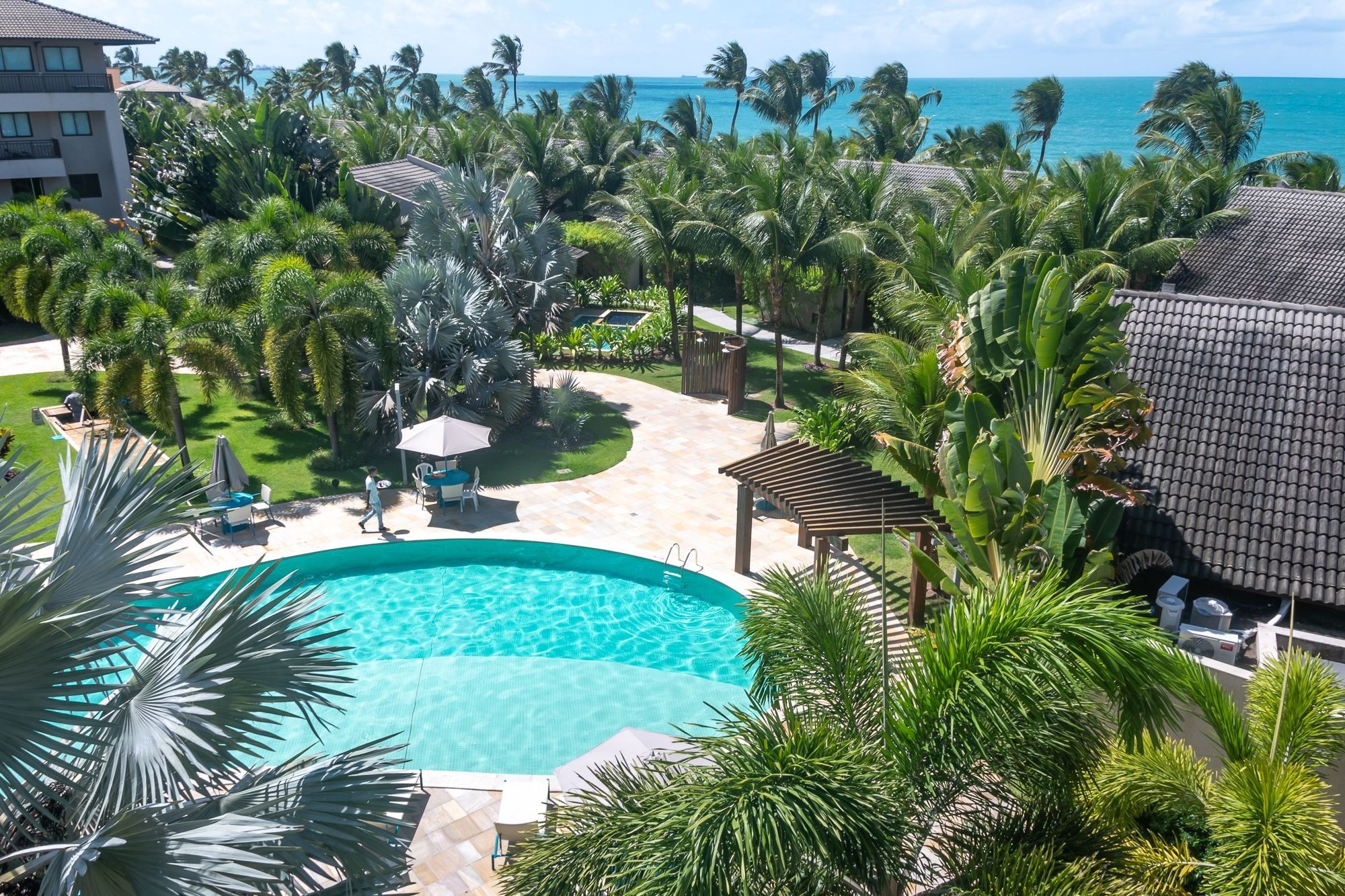 Un resort con piscina, palmeras y vista al océano.