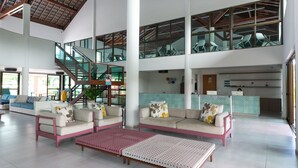 Eine geräumige Lobby mit hoher Decke, einer Treppe und einem Empfangsbereich.