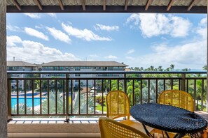 A balcony with a view of a swimming pool, a building in the background, and two yellow chairs. - BeachClass EcoLife Porto de Galinhas (Ipojuca)