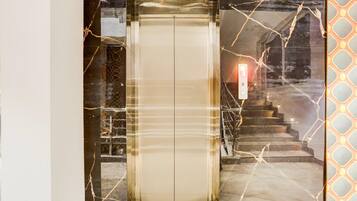 An elevator with a marble wall design and a staircase with a patterned wall to the right.