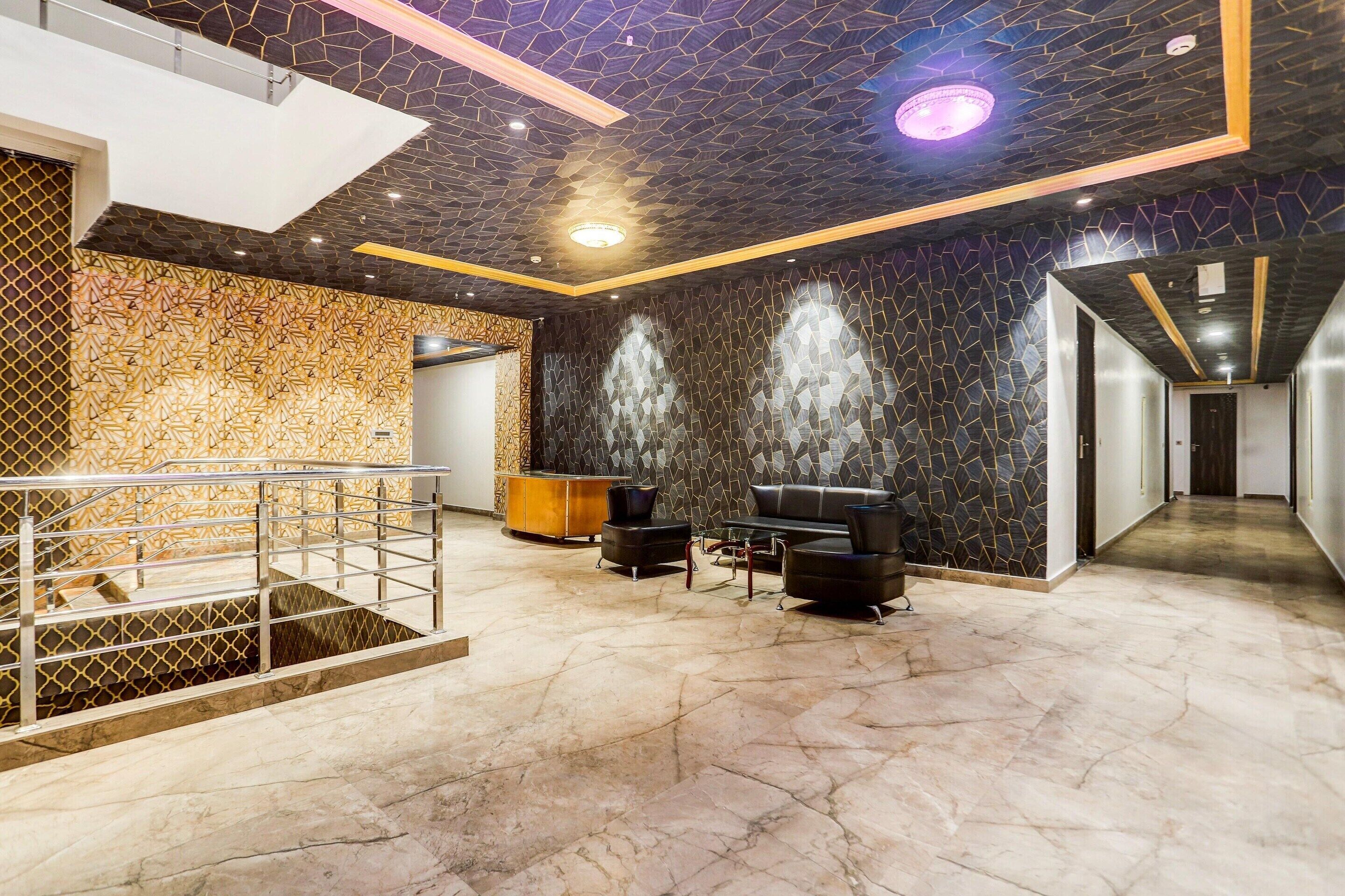 Un hall d’entrée doté d’un sol en marbre, d’un comptoir de réception, d’un escalier et d’un espace détente au design moderne.