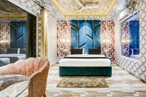 Quarto moderno com uma cama grande, área de estar com uma poltrona e paredes estampadas.