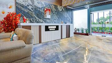 Un espace d’accueil avec un mur en marbre, une enseigne indiquant « PALETTE, services aux entreprises », et un coin salon avec des coussins à motifs.