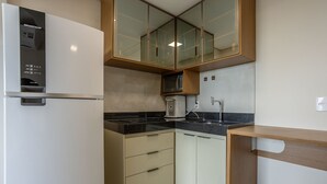 Eine kleine Küche mit Kühlschrank, Mikrowelle und Spüle.