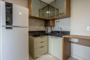 Eine kleine Küche mit Kühlschrank, Mikrowelle und Spüle.