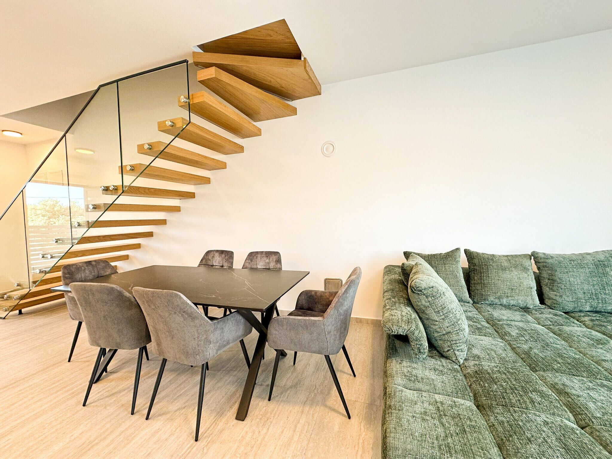 A modern interior with a dining area, a staircase, and a sofa.