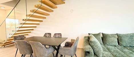 A modern interior with a dining area, a staircase, and a sofa.