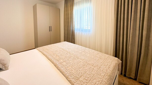 Quarto de hotel com cama, armário e janela com cortinas.