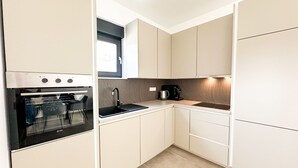 Uma cozinha compacta com forno embutido, pia e cafeteira.