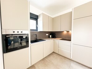 Eine kleine Küche mit Backofen, Spüle und Kaffeemaschine.
