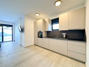 A modern kitchen with built-in appliances, a window, and a view of the outdoors. - Villa Sorelle 1 & Sorelle 2 (Zaton)