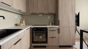 Een moderne keuken met houten kastjes, een zwarte kookplaat en een inbouwoven.