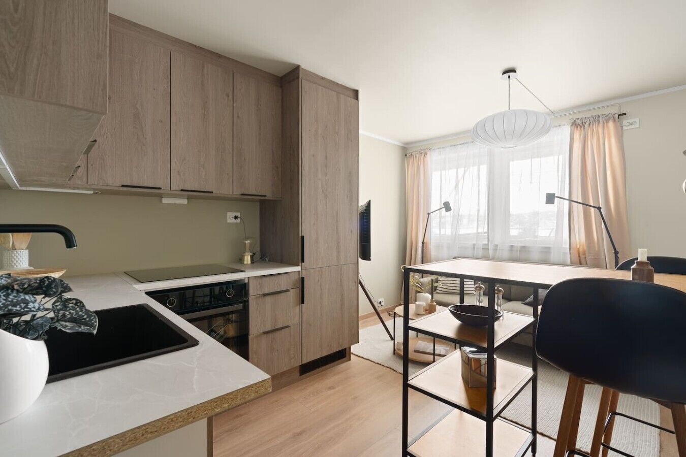 Una cocina moderna con armarios de madera, una encimera blanca y una zona de comedor con una mesa y sillas.