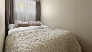 Een slaapkamer met een bed, gordijnen en een raam.