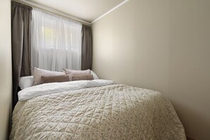 A bedroom with a bed, curtains, and a window. - Bright & Cozy Studio Apartment (Tromsø)
