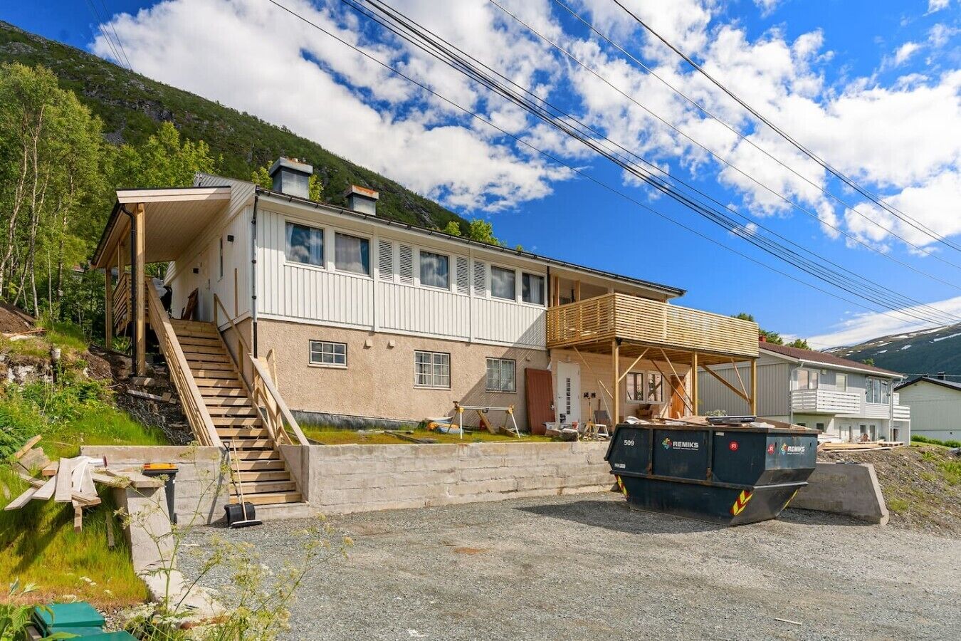 A two-story house with a wooden staircase leading to a covered porch.