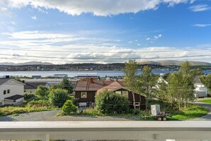 A residential area with a house in the foreground, a body of water in the background, and a hilly landscape. - Bright & Cozy Studio Apartment (Tromsø)