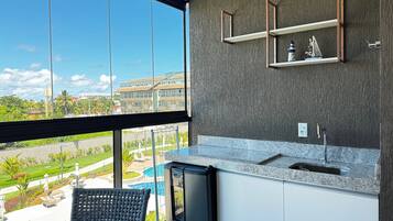 Una cocina moderna con un ventanal grande, un lavamanos integrado y vistas a una piscina y edificios.