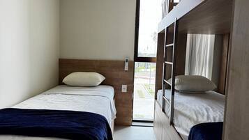 A compact room with two beds, one with a headboard and the other with a bunk.