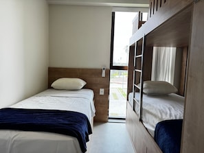 Una habitación compacta con dos camas, una con cabecera y otra literas.