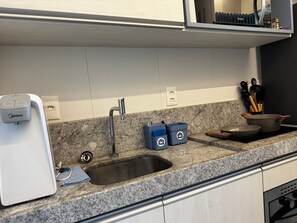 Et moderne køkken med en granitbordplade, stålvask og et indbygget ovn.