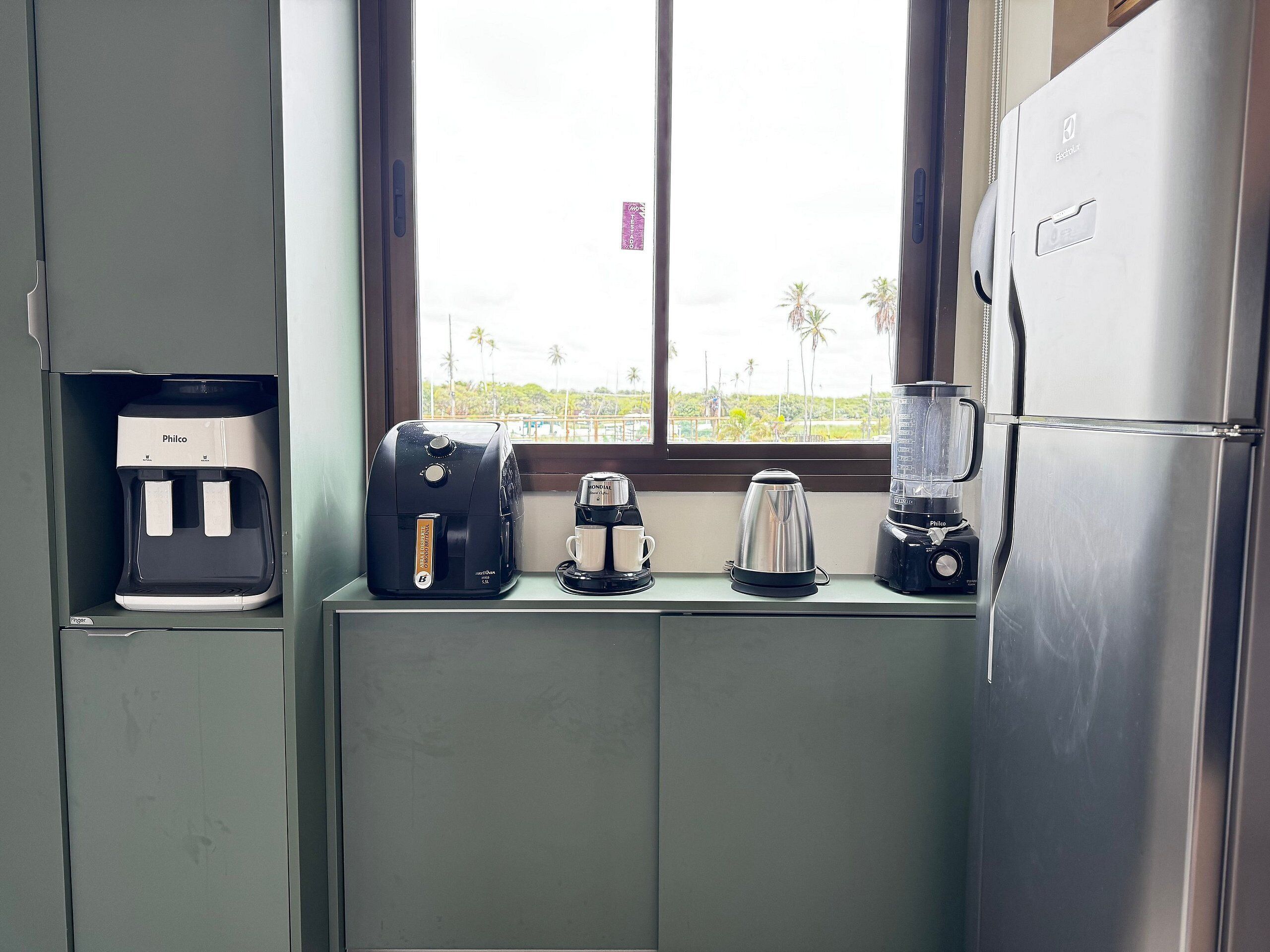 A kitchenette with a coffee maker, a kettle, and a blender on a counter.