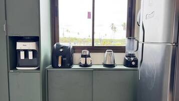 A kitchenette with a coffee maker, a kettle, and a blender on a counter.