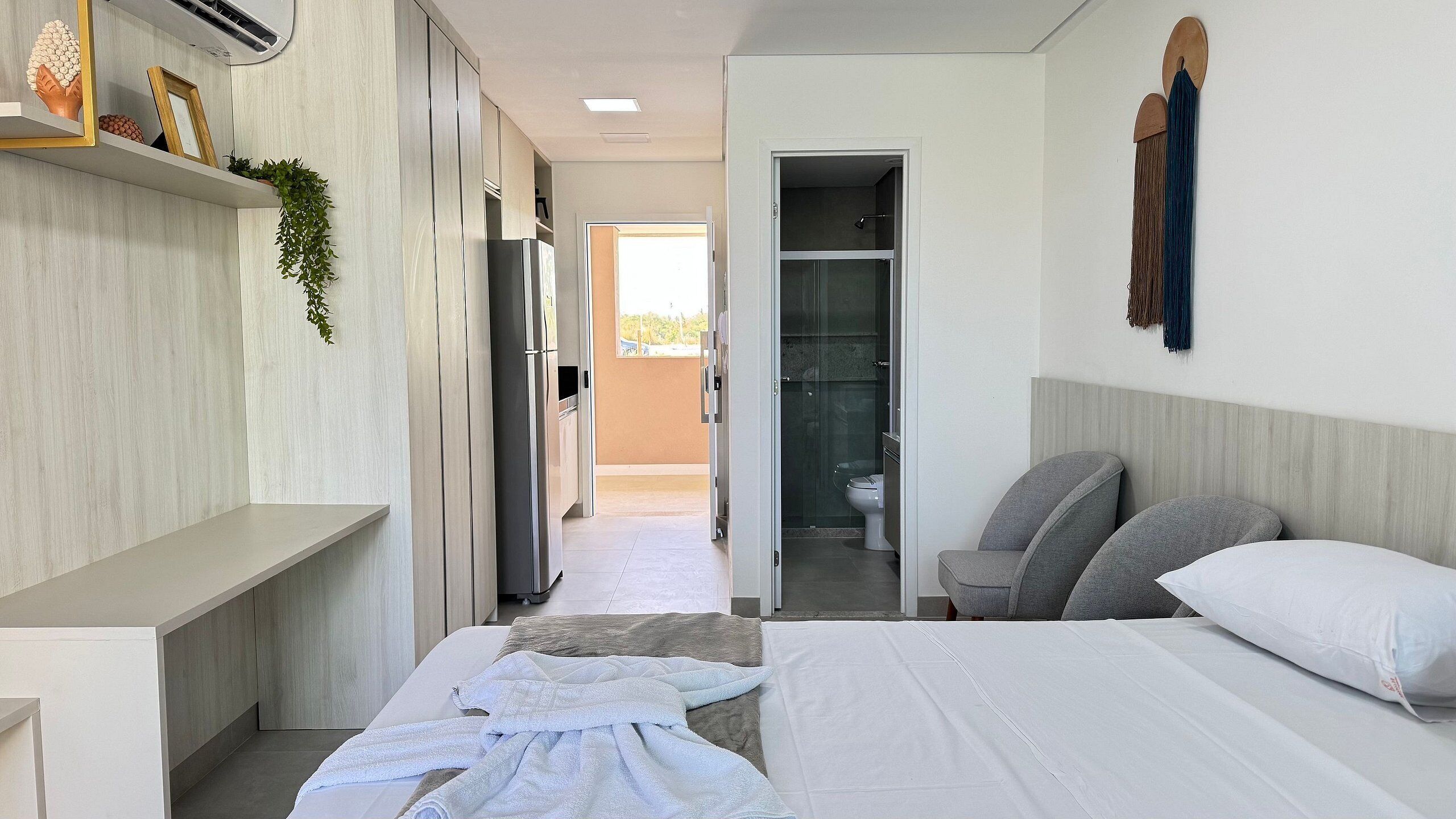 Habitación de hotel con cama, mesita de noche, armario y baño visible a través de una puerta abierta.
