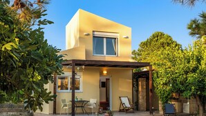 Une maison moderne à deux étages, dotée d’un patio couvert, d’un espace salon extérieur et d’un jardin.