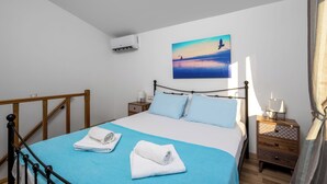 Une chambre à coucher avec un lit, une table de chevet, un appareil de climatisation et un tableau au mur.