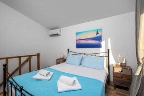 Ein Schlafzimmer mit einem Bett, einem Nachttisch, einer Klimaanlage und einem Bild an der Wand.
