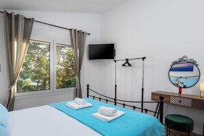 A hotel room with a bed, a TV, a mirror, and a window with curtains. - Tasos By the Sea (Rhodes)