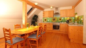Uma cozinha com armários de madeira, uma mesa de jantar com cadeiras e um mural com girassóis na parede.